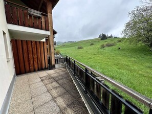 En balkon med trægelænder, der ud til et grønt græsareal.