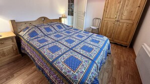 A bedroom with a wooden bed, a wooden wardrobe, and a bedside table with a lamp. - 1st floor, balcony, tv, 35m², Villard de Lans (Villard-de-Lans)