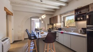 Una cocina moderna con una isla central, taburetes de bar y un ventanal con vistas a un jardín.