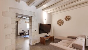 Un salón con un sofá color beige, un televisor y dos adornos en la pared.