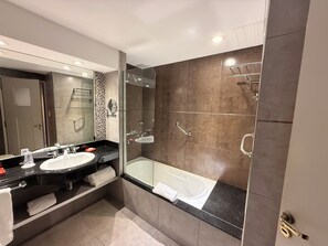 Une salle de bain moderne avec deux lavabos, une douche à parois de verre et une baignoire.