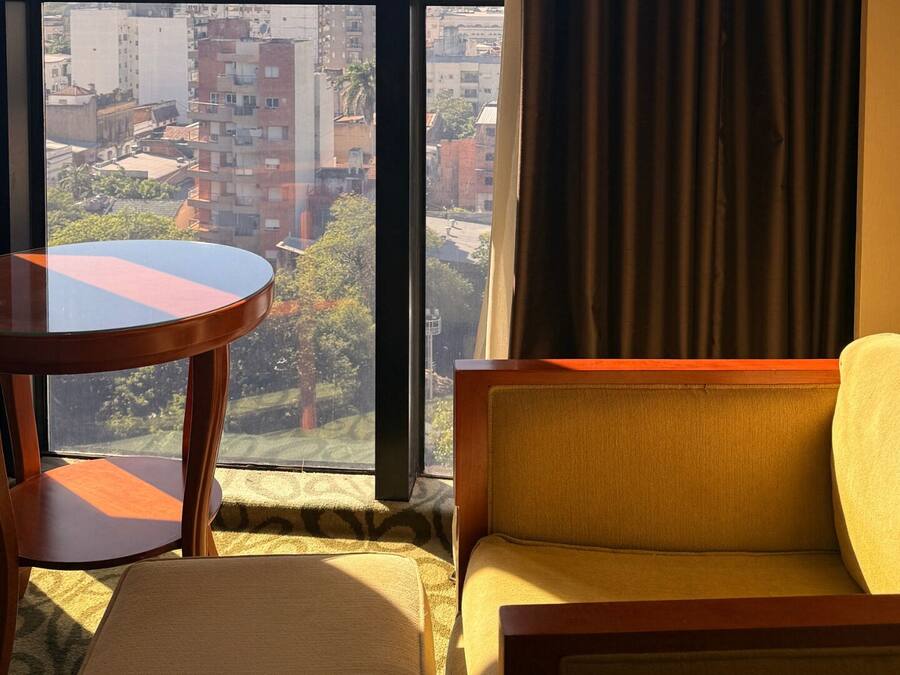 Ein Hotelzimmer mit einer Couch, einem kleinen runden Tisch und einem großen Fenster mit Blick auf die Stadt.