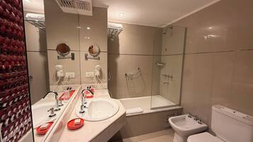 A modern bathroom with a large mirror, a bathtub, a shower, and a toilet.