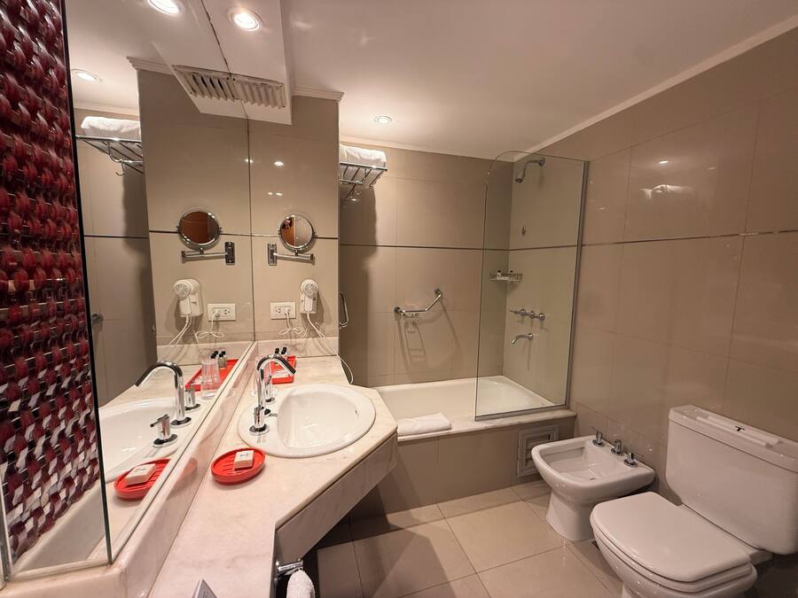 A modern bathroom with a large mirror, a bathtub, a shower, and a toilet.
