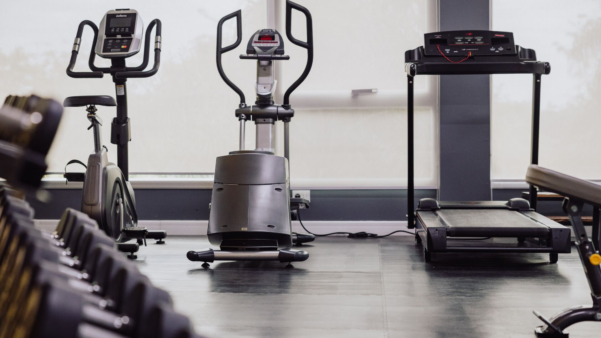 A gym with cardio machines, a treadmill, and weight benches.