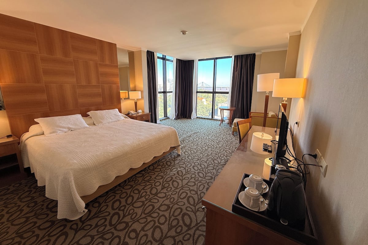 Een hotelkamer met een groot bed, een bureau met een computer, een stoel en uitzicht op de omgeving.