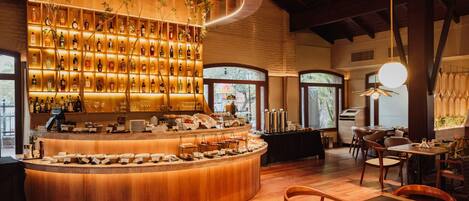 A bar area with a curved counter, shelves of liquor bottles, and a buffet setup.