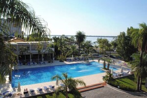 Una piscina techada, una piscina al aire libre, sombrillas
