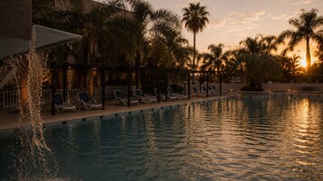 Una piscina techada, una piscina al aire libre, sombrillas
