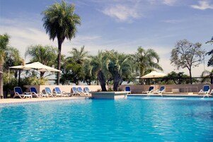 Una piscina techada, una piscina al aire libre, sombrillas