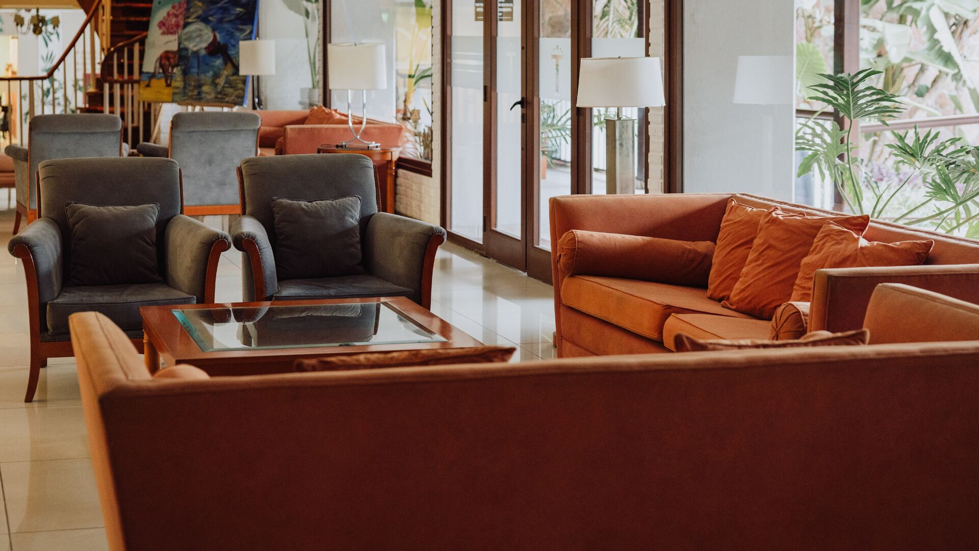 Una sala de estar moderna con sofás de cuero, una mesa de centro de vidrio y una escalera con barandilla.