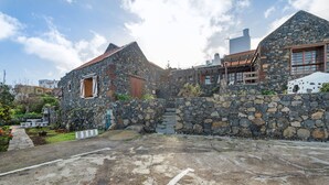 Un edificio de piedra con techo inclinado, una puerta de madera y un camino de acceso de concreto.