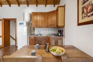 Une cuisine avec des meubles de rangement en bois, un four à micro-ondes, une machine à café et un saladier rempli de fruits posé sur le comptoir.