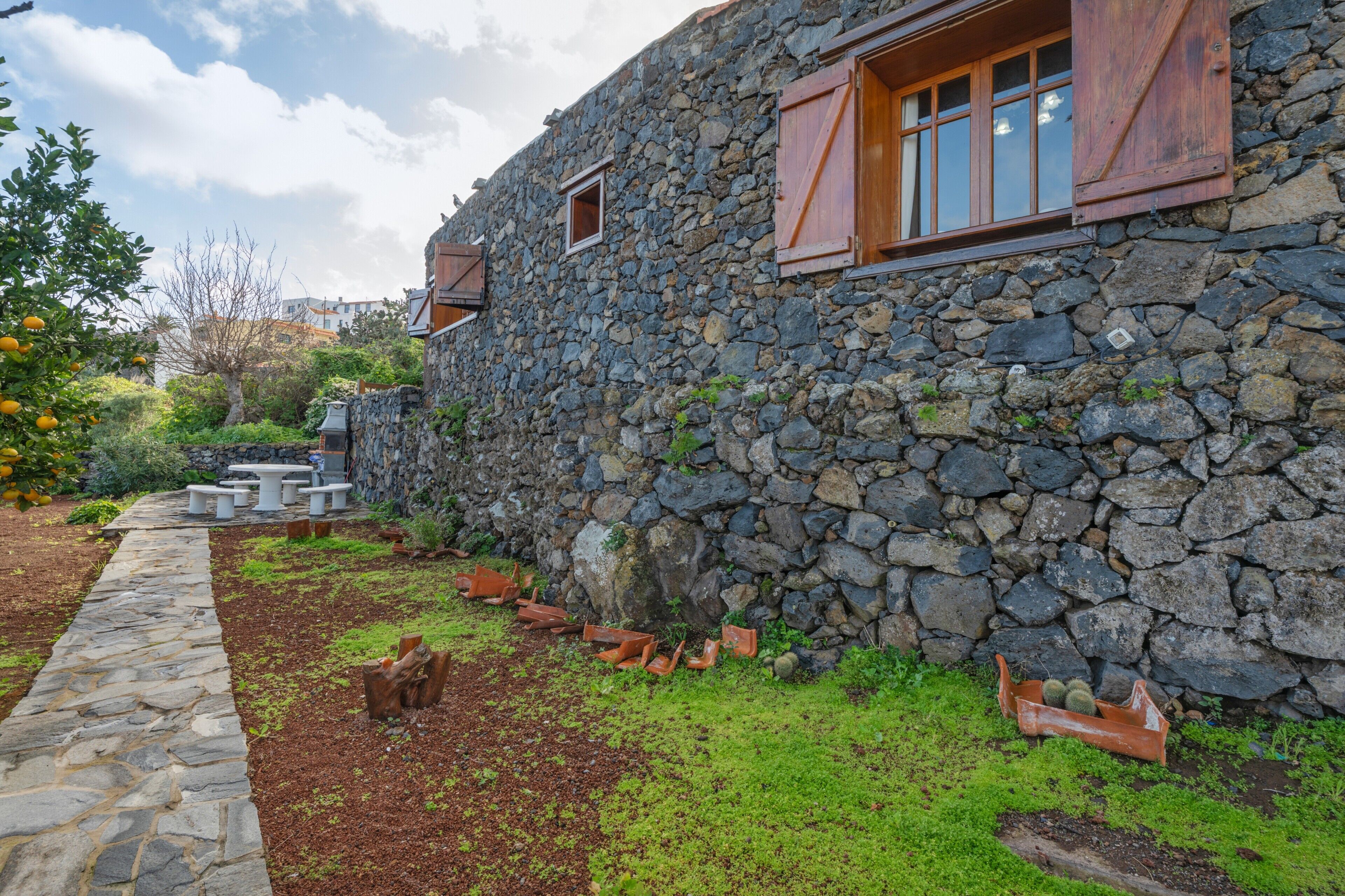 A stone building with a stone pathway, outdoor seating, and a garden area.
