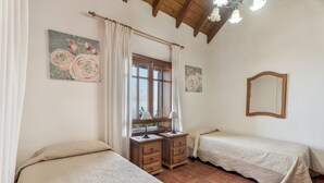A bedroom with two beds, a window with curtains, a bedside table with lamps, and a mirror on the wall. - Country House 'El Almendro' with Sea Views, Shared Terrace and Wi-Fi (El Mocanal)