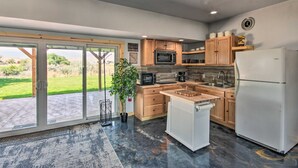 Een moderne keuken met houten kastjes, een witte koelkast en een groot raam met uitzicht op een groen landschap.