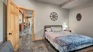 Een slaapkamer met een bed, een plafondventilator, een wandklok en een deur naar een andere kamer.