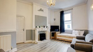 A modern living room with a fireplace, a television, and a sofa. - Pass the Keys | Spacious 4-Bedroom Maisonette in Central Newcastle (Newcastle)