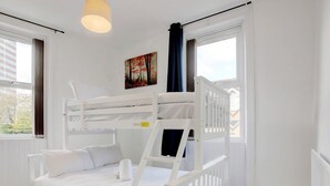 A bunk bed room with white bedding, a painting on the wall, and a window with curtains. - Pass the Keys | Spacious 4-Bedroom Maisonette in Central Newcastle (Newcastle)