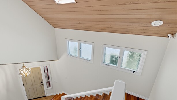 A staircase with wooden steps and white railings, leading to a landing with a door and a window.