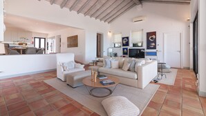 Amplia sala de estar con techo alto, un conjunto de sofás, una mesa de centro y un televisor.