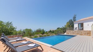 Una piscina con sillones de descanso, una pared de piedra y una cubierta de madera.
