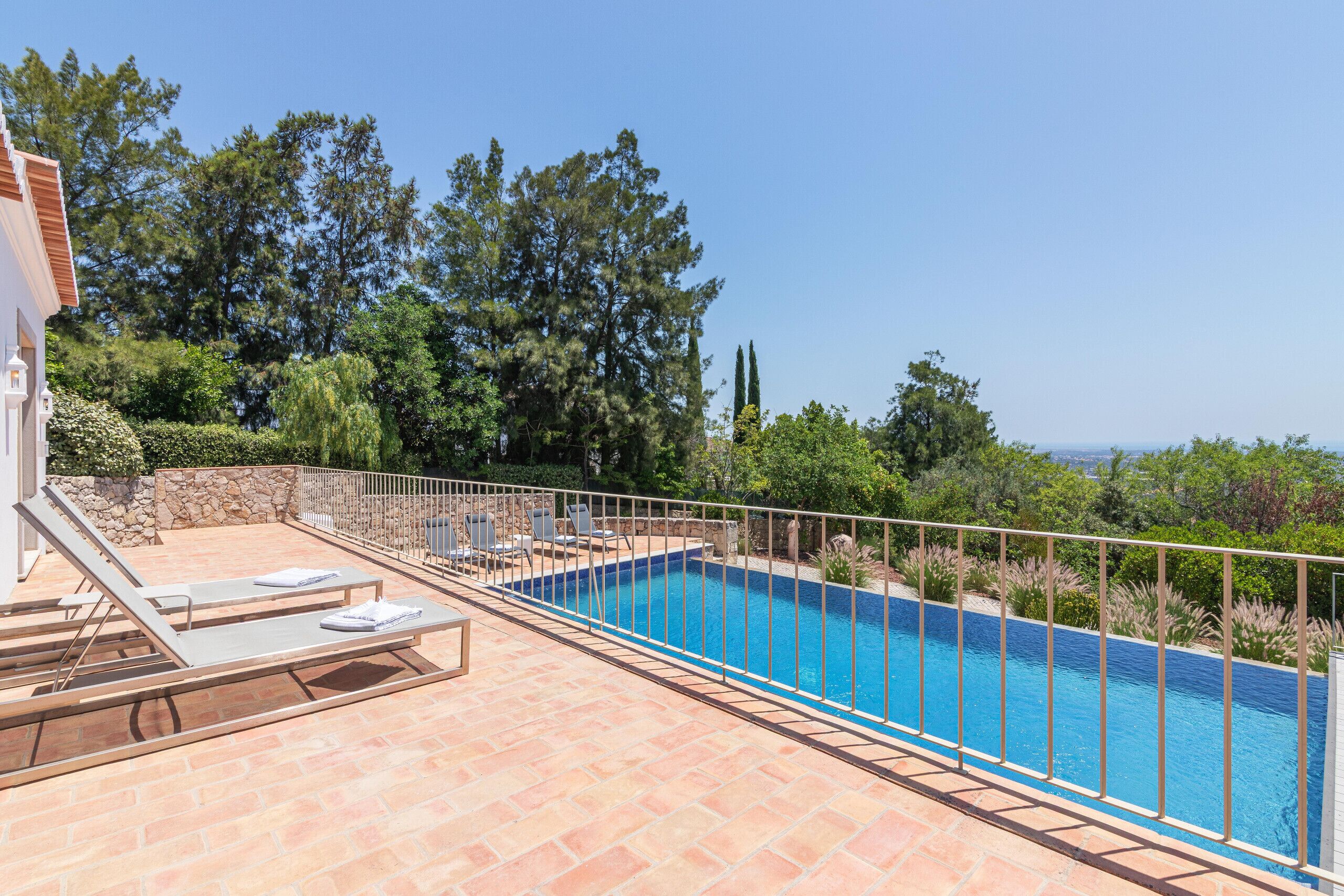 Ein Swimmingpool mit Liegestühlen und einer Steinmauer.