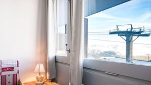 A room with a window overlooking a mountain and a cable car.
