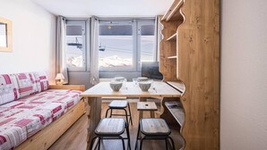 A cozy room with a wooden table, two chairs, a bench, and a window with a view of a snowy landscape.