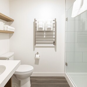 Ein modernes Badezimmer mit Toilette, Handtuchhalter und einer Duschkabine aus Glas.