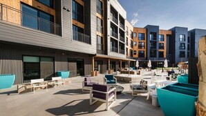 A modern outdoor seating area with multiple tables and chairs, a fire pit, and a stone wall. - The Ski Pad by Park City Vacations (Park City)