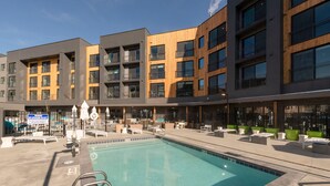 A modern building with a swimming pool, outdoor seating, and a sign indicating no lifeguard on duty. - The Ski Pad by Park City Vacations (Park City)