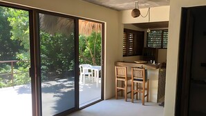 A modern kitchen with a bar area, a sliding glass door leading to a balcony, and a dining area with chairs. - Xolo. Loft junto al mar Adultos . Starlink. A/Ac. (Santa María Colotepec)