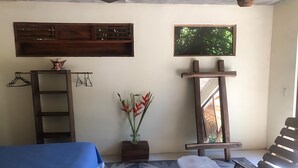 A room with a bed, a bench, a wooden shelf, a mirror, and a window with a view of greenery. - Xolo. Loft junto al mar Adultos . Starlink. A/Ac. (Santa María Colotepec)