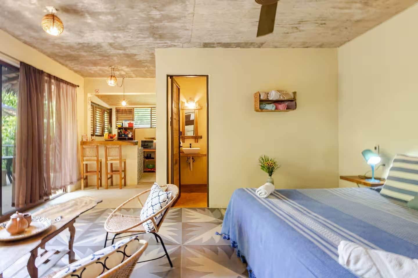 Une chambre d’hôtel comprenant un lit, une chaise, une petite table, un bureau et une kitchenette.