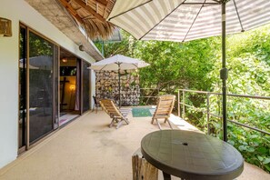 A covered outdoor area with a pool, two wooden chairs, a table, and a striped umbrella. - Xolo. Loft junto al mar Adultos . Starlink. A/Ac. (Santa María Colotepec)