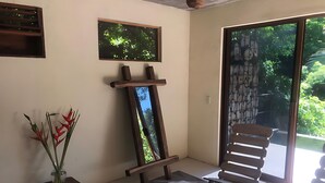 A room with a large mirror, a wooden bench, a table with a white cloth, and a vase with red flowers. - Xolo. Loft junto al mar Adultos . Starlink. A/Ac. (Santa María Colotepec)