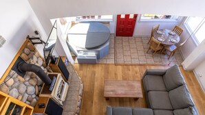 Un salon chaleureux avec une cheminée en pierre, un canapé, une table basse et une table à manger avec des chaises.