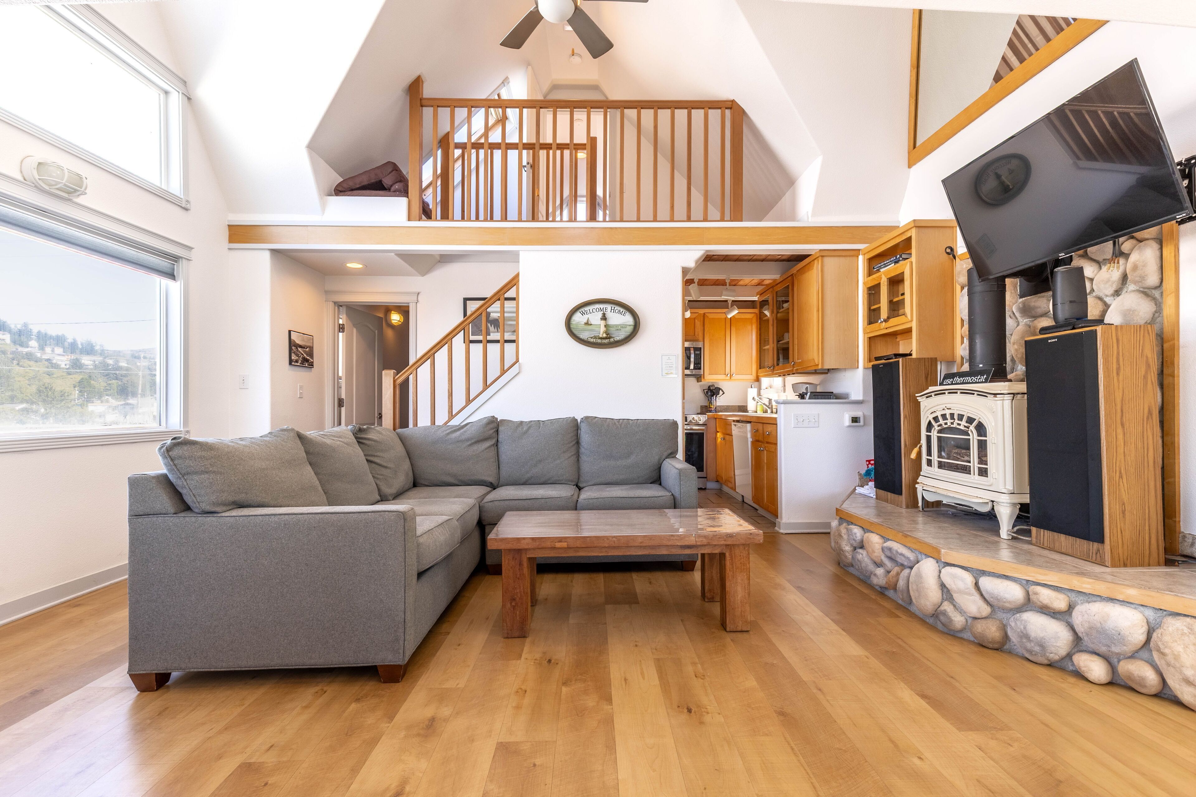 A modern living room with a sectional sofa, a wooden coffee table, and a stone fireplace.
