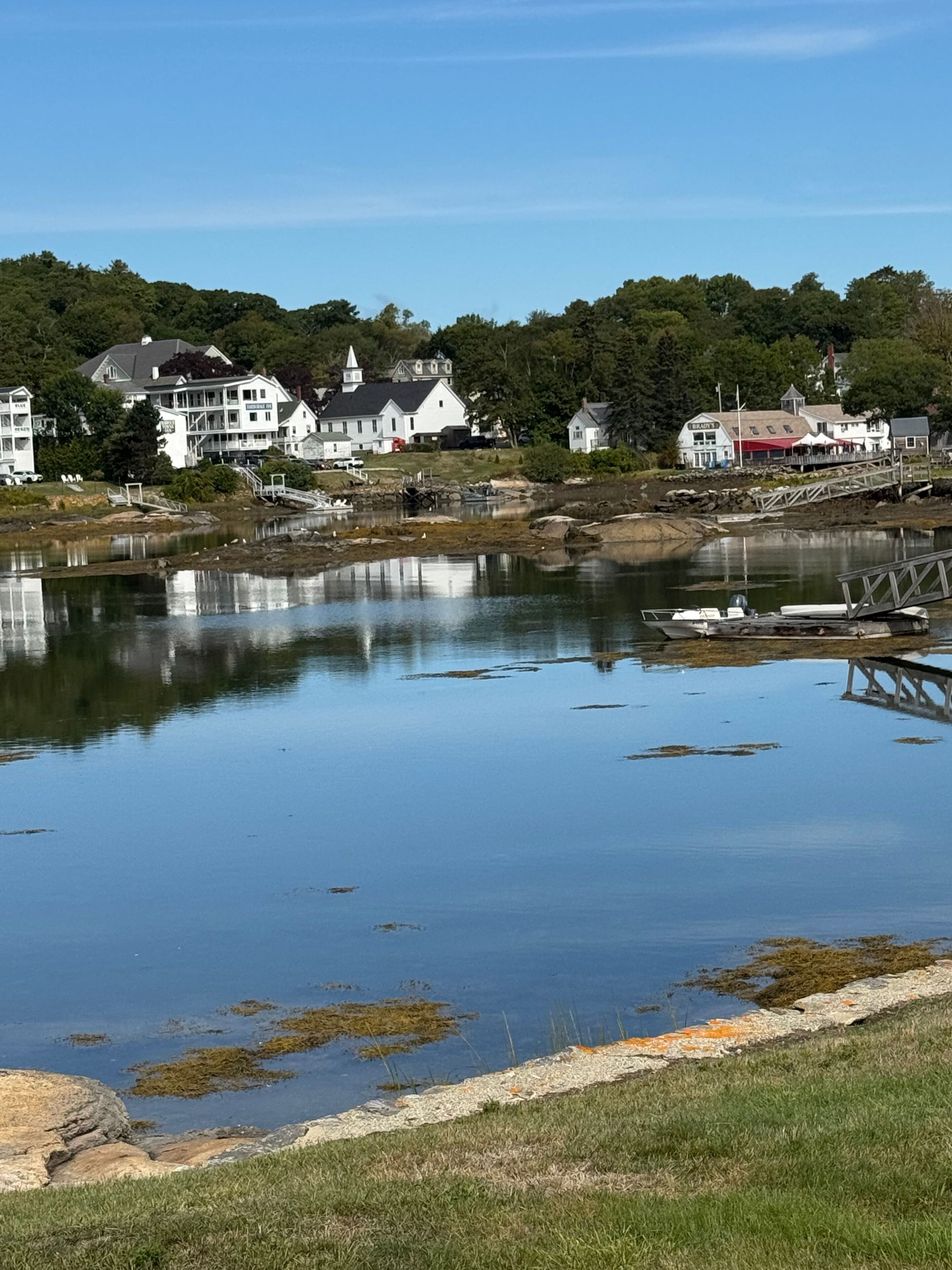 A waterfront property with a dock, a small boat, and a building with a red roof.