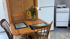 Un tavolo da pranzo in legno con sedie, un vaso con fiori, un frigorifero e un fornello.