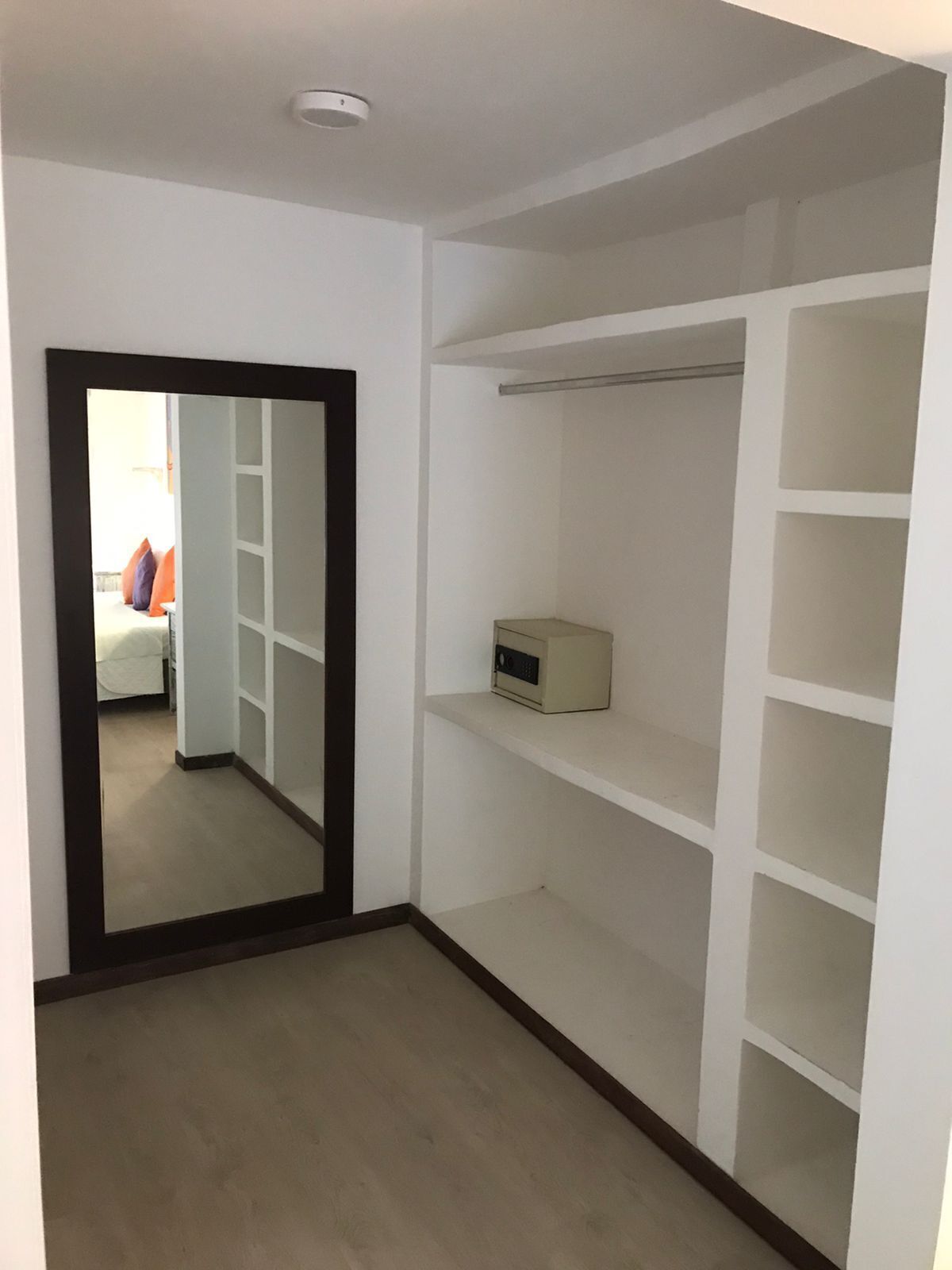 A walk-in closet with open shelving and a small appliance on the top shelf.