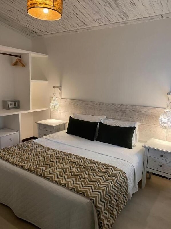 A modern bedroom with a bed, bedside tables, a hanging light fixture, and a wall-mounted shelf. - Pousada dos Girassóis (Tibau do Sul)