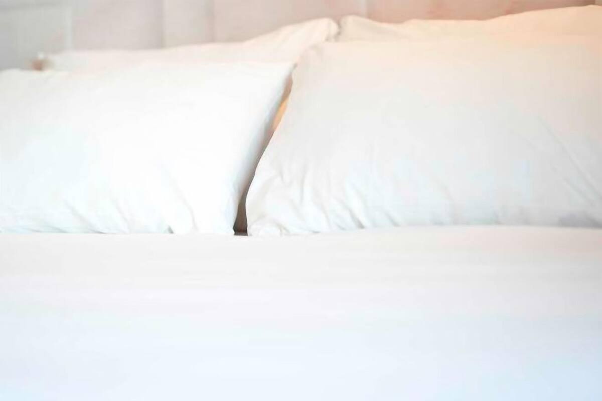 Een bed met witte lakens en kussens.
