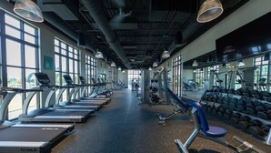 Ein Fitnessstudio mit Laufbändern, Kraftgeräten und Kurzhanteln.