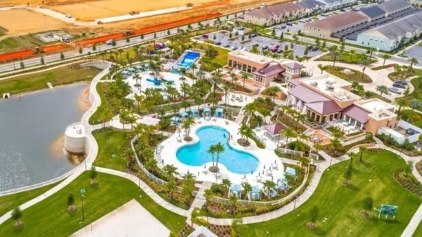 Luftaufnahme eines Resorts mit einem zentralen Schwimmbecken, einem großen Wassertank und einem Parkplatz mit mehreren Gebäuden.