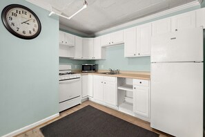 A kitchen with white cabinets, a stove, a microwave, and a refrigerator. - Oceanfront Boardwalk Getaway | Steps to Beach | Sleeps 6 (Ocean City)