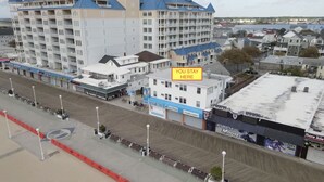 Un hotel frente al mar con varios pisos y un paseo marítimo, además de diversas tiendas.
