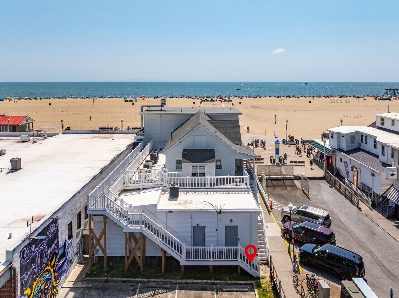 Un immeuble situé en bord de mer, doté d’un balcon, d’un espace de stationnement et offrant une vue sur la plage.