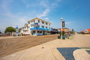 A boardwalk with shops, including a funnel cake stand, and a clear blue sky.